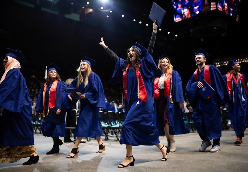 密歇根州立大学丹佛 graduates walk off the Commencement stage with their diplomas.