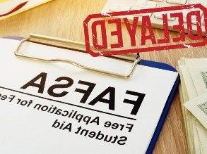 Picture of a form on a clipboard that says FAFSA at the top, with red letters spelling 'DELAYED' stamped on top of it.